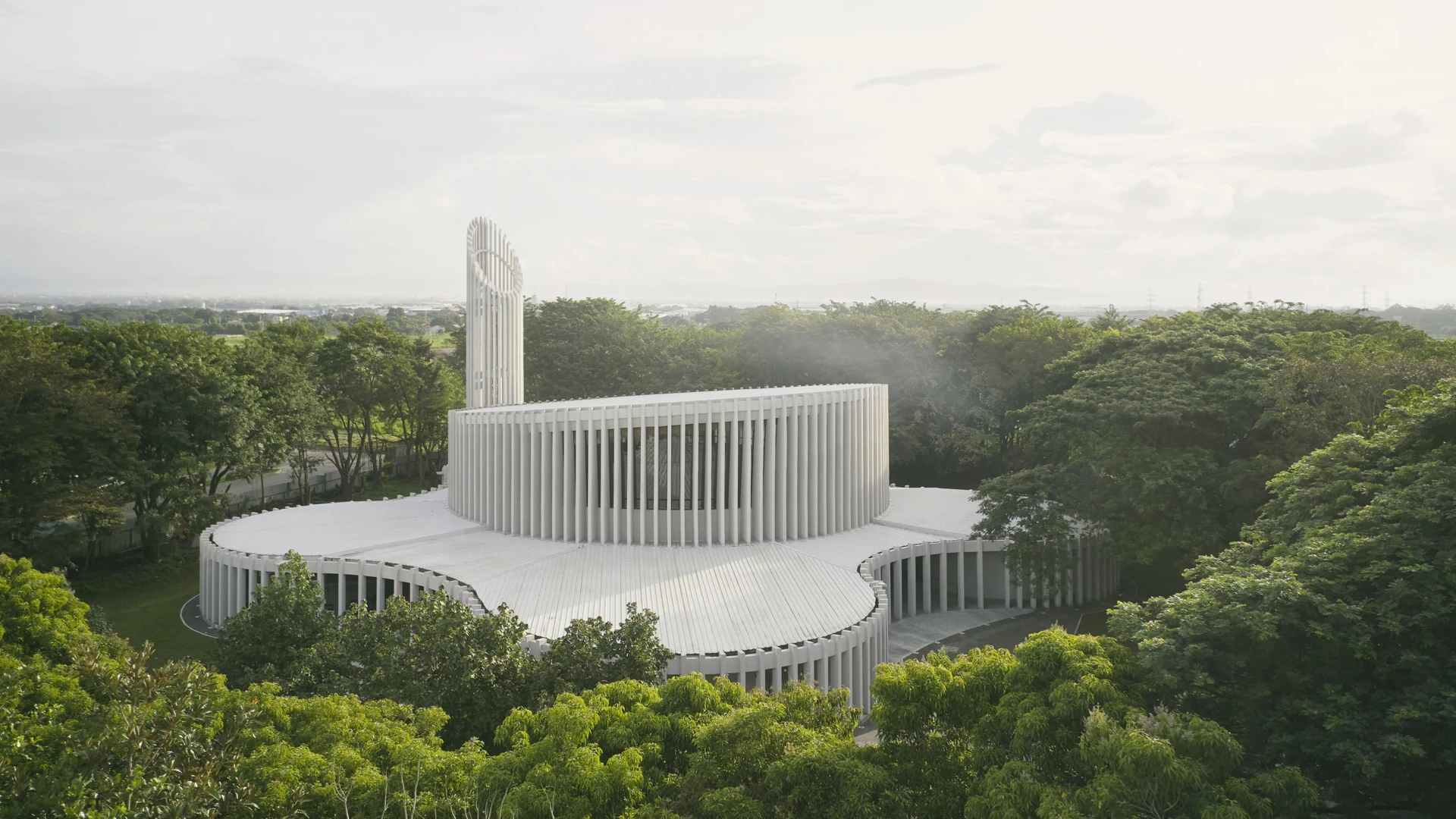 Aerial view of CAZA’s Santuario de La Salle in Biñán, Philippines, showcasing its façade and circular structures nestled within surrouding lush greenery.